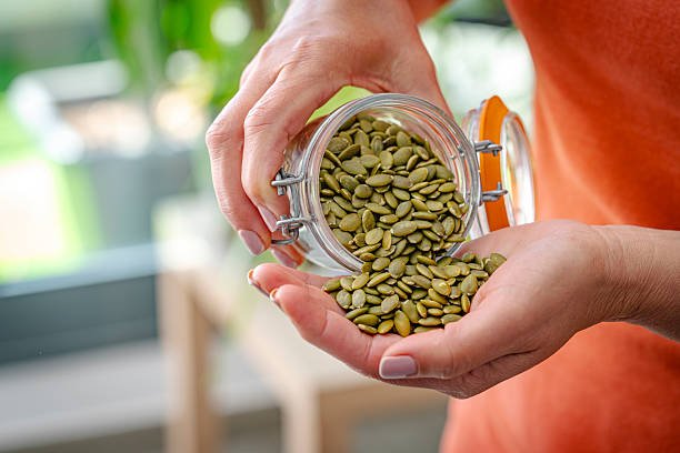 woman eating fresh organic pumpkin seeds woman eating fresh organic pumpkin seeds