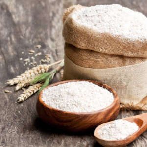 whole grain flour in a wooden bowl and sackcloth bagwith ears